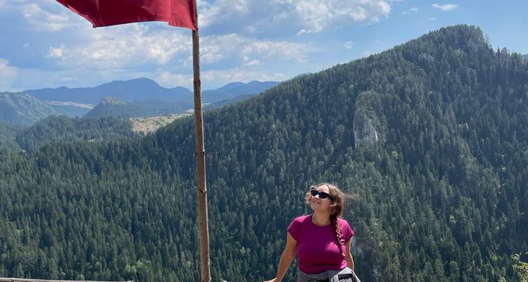 Vrouw staat bij een rode vlag en geniet van panoramische uitzichten over beboste bergen.