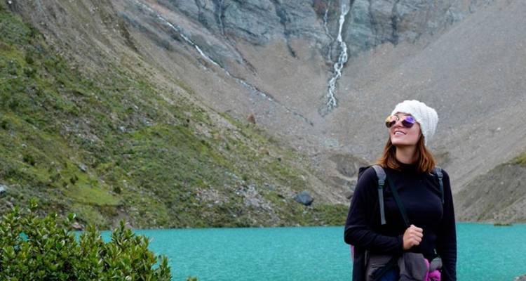 Personne regardant un lac turquoise entouré de montagnes.