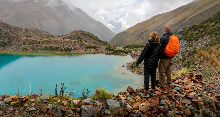 Couple debout au bord d'un lac avec un paysage montagneux.