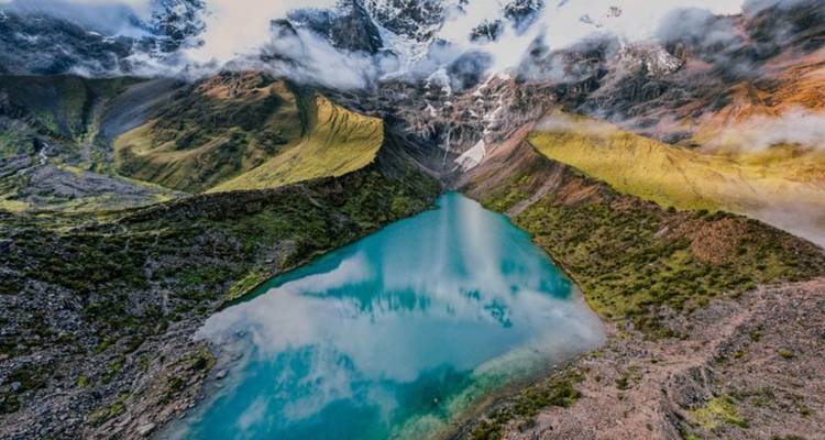 Vue aérienne d'un lac turquoise dans une vallée de montagne.