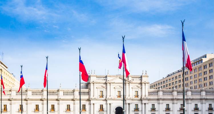 Government palace with national flags against a clear blue sky.