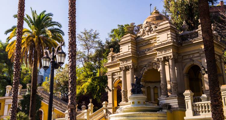Historic building with palm trees and a fountain.