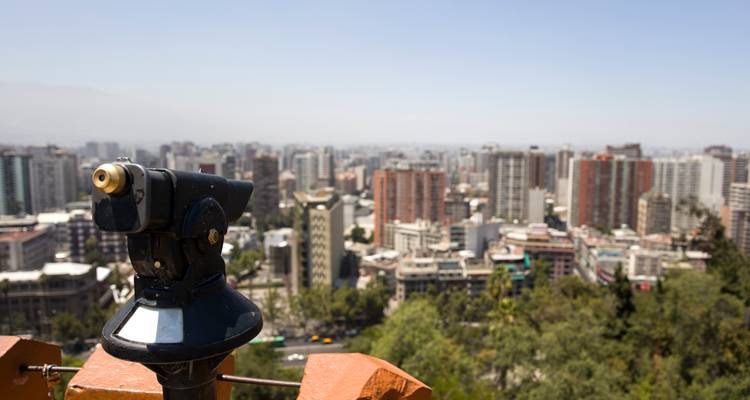 Telescope overlooking a city skyline with numerous buildings.