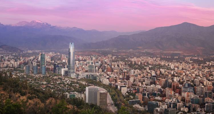 Cityscape at sunset with mountains in the background.