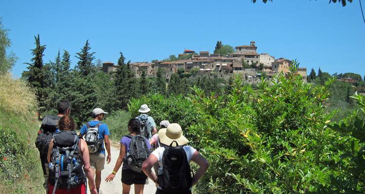 Randonnée en groupe vers un village pittoresque entouré de verdure.