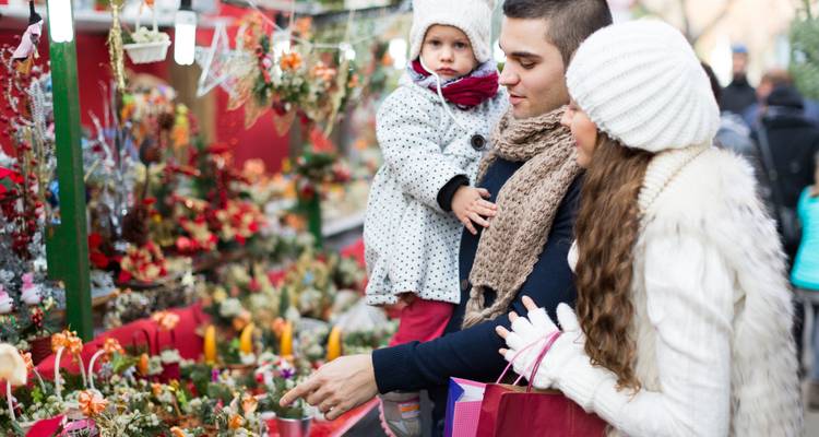 Familia paseando por un mercado navideño con decoraciones florales.