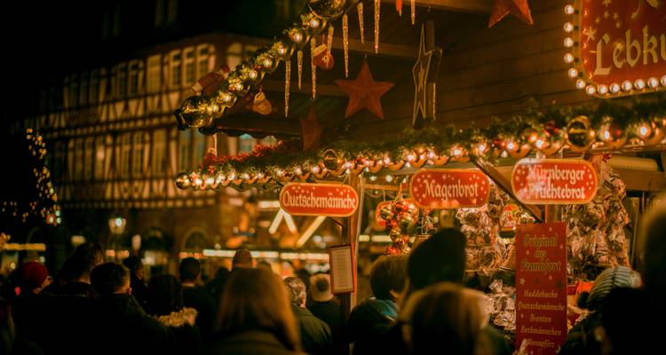 Multitud disfrutando de un mercado nocturno con luces festivas.