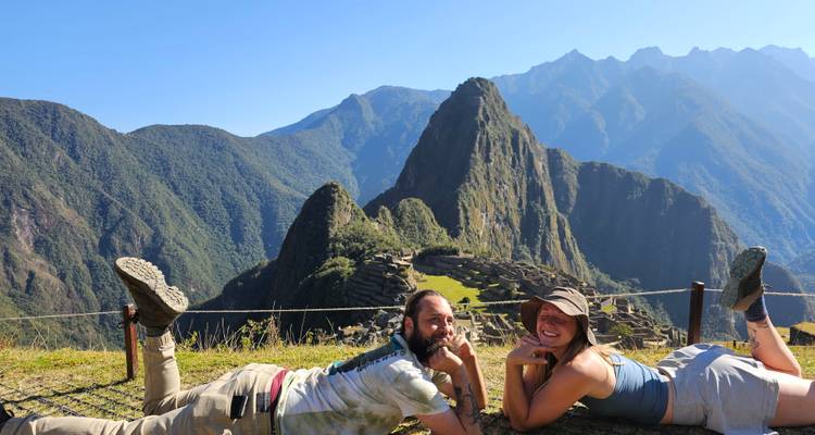 Deux personnes allongées sur l'herbe avec le Machu Picchu en arrière-plan.