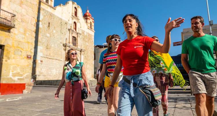 Groupe de touristes marchant près d'un bâtiment historique sous un ciel bleu dégagé.