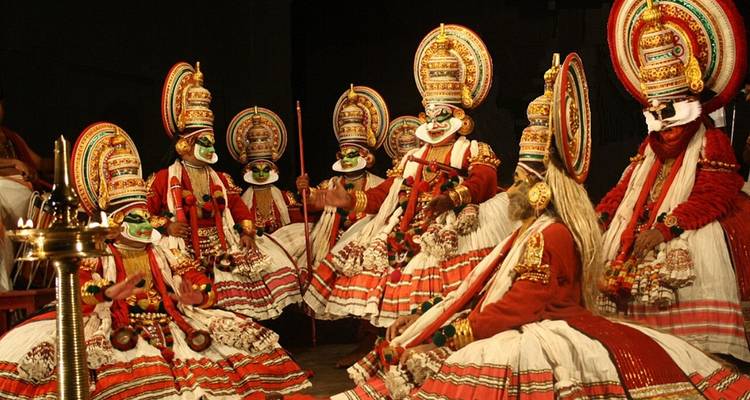 Traditional dancers wearing elaborate costumes, performing indoors.
