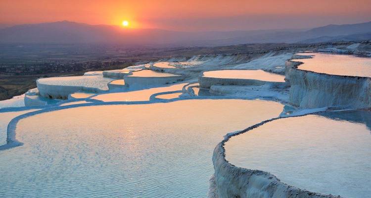 Bassins en terrasses de Pamukkale reflétant les couleurs du coucher de soleil.