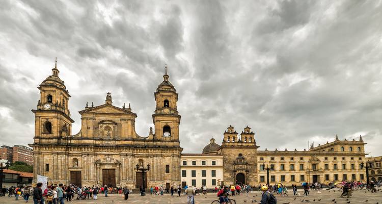 Place Bolívar bondée avec cathédrale et bâtiments coloniaux sous un ciel dramatique et nuageux à Bogotá