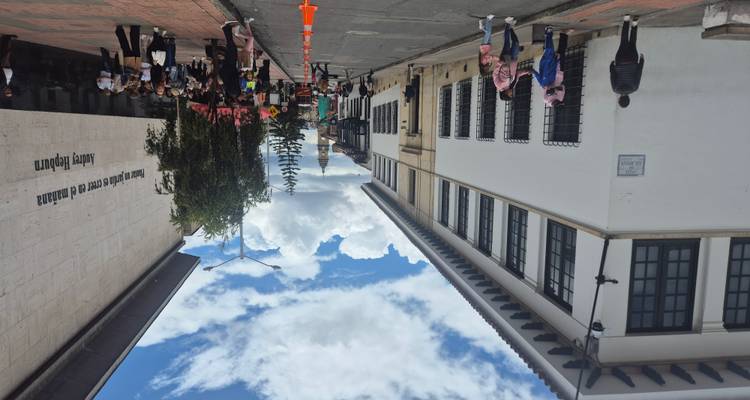 Drukke voetgangersstraat in Bogotá's historische wijk met witte koloniale gebouwen en bewolkte lucht.