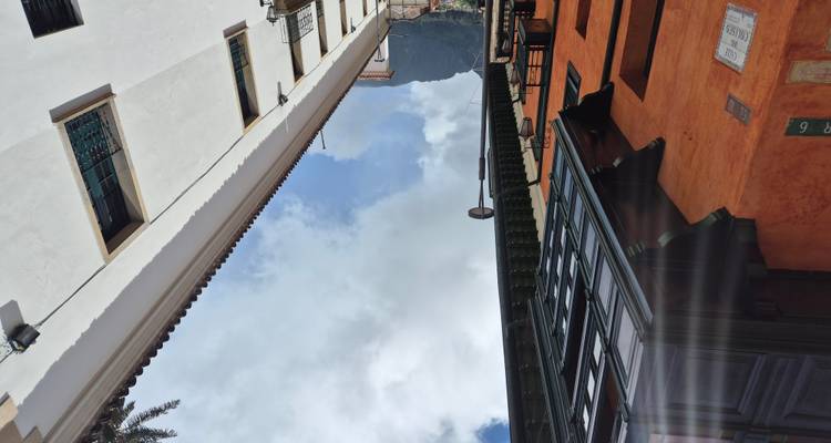 Opwaarts straatgezicht tussen oranje en witte koloniale gebouwen richting een berg in de verte.