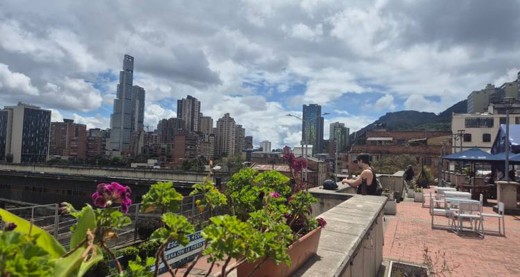 Dakterras café met bloemen met uitzicht op moderne wolkenkrabbers van Bogotá en bergen.