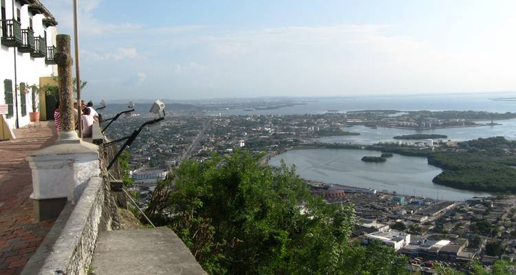 Point de vue élevé surplombant une ville côtière, les eaux de la baie, des îles et l'horizon lointain sous un ciel clair.