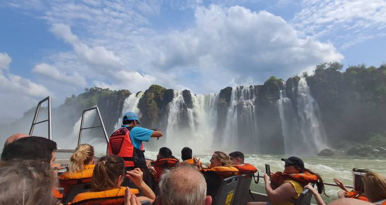 Een avonturenboot vol toeristen in reddingsvesten vaart naar de bulderend watervallen van Iguazú.
