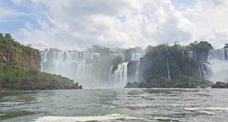 Breed, mistig vooraanzicht van meerdere Iguazú-watervallen die in de rivier storten, omgeven door jungle.