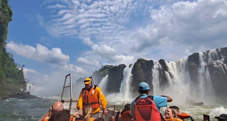 Speedboot met helmdragers aan boord en passagiers vaart af op de donderende watervallen van Iguazú.