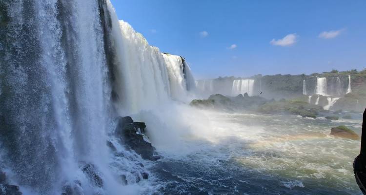 Dicht uitkijkpunt naast massieve gordijnen van de Iguazú-waterval met mist en een zwakke regenboog.