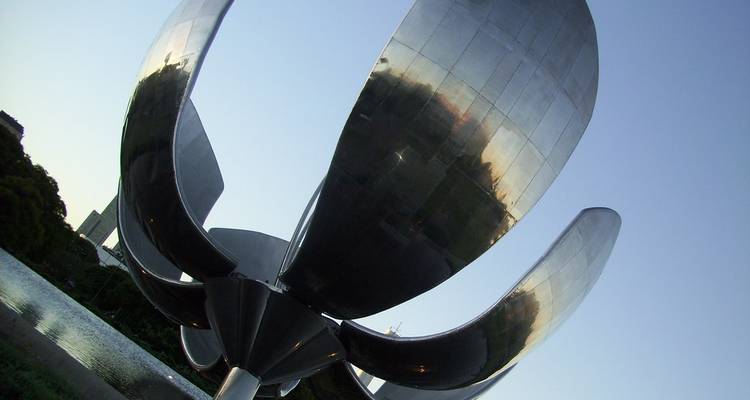 Les pétales métalliques de la sculpture Floralis Genérica reflètent la lumière du soir contre le ciel.