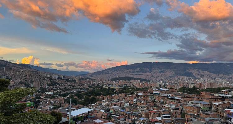 Vue panoramique du coucher de soleil sur les quartiers de Comuna de Medellín et les montagnes environnantes sous des nuages lumineux.