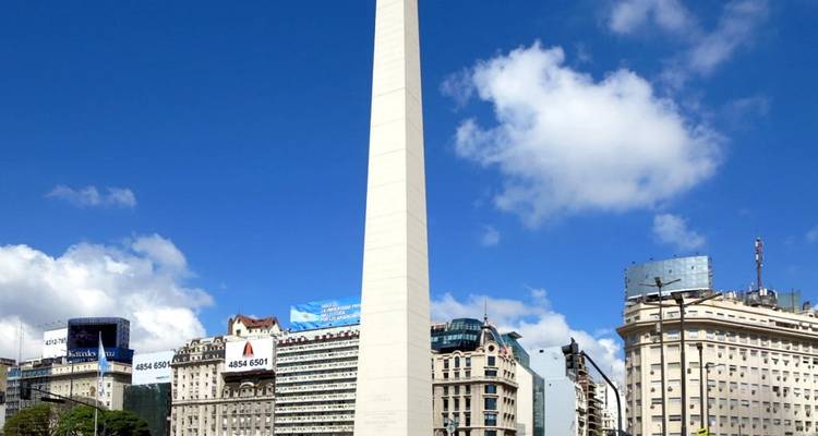 L'Obélisque de Buenos Aires s'élève dans un ciel bleu profond encadré par des bâtiments classiques de la ville.