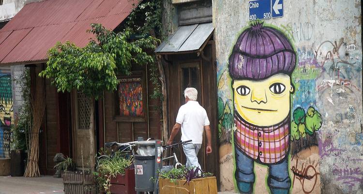 Mur couvert de graffitis à San Telmo présentant un personnage de dessin animé coloré tandis qu'un passant marche devant.