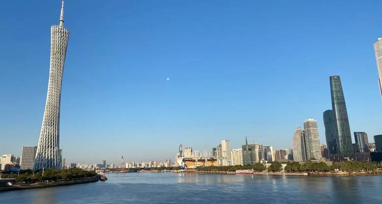 Une large vue sur la rivière avec la Tour de Canton et des bâtiments modernes.
