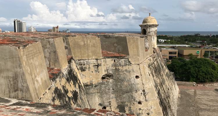 Bastions de pierre de la forteresse de Carthagène surplombant le paysage urbain et la mer des Caraïbes sous un ciel nuageux.