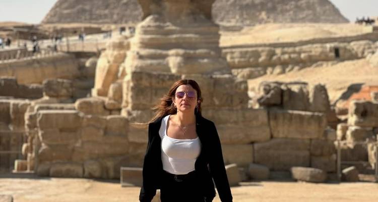 Een persoon voor de Sfinx met de piramide op de achtergrond.