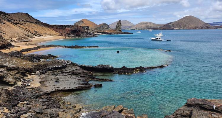 Costa volcánica espectacular y aguas turquesas de las Galápagos con yates anclados cerca