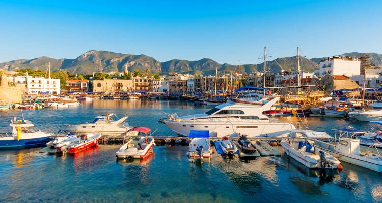 Harbor with boats and mountains at sunset.