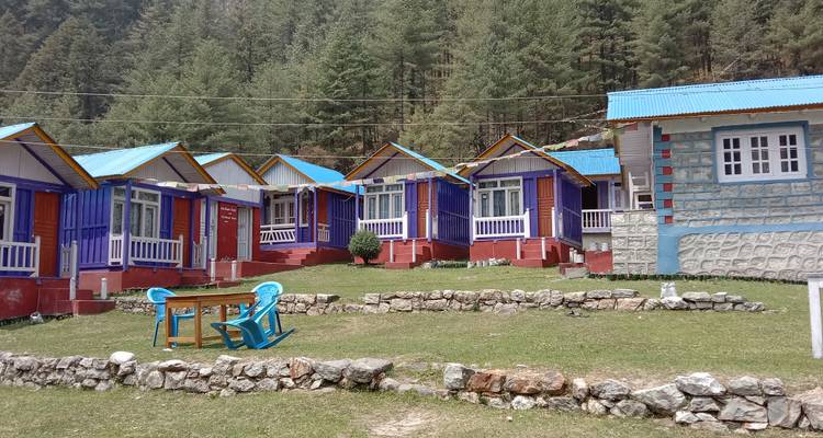 Rangée de petits chalets colorés dans un cadre forestier.