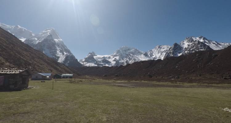Vue sur une large vallée entourée de montagnes enneigées.