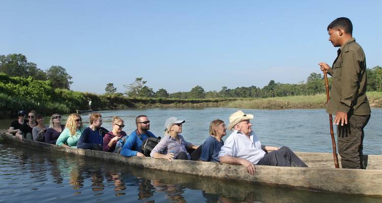Touristen in einem Einbaum auf einem ruhigen Fluss in einer Dschungelumgebung.