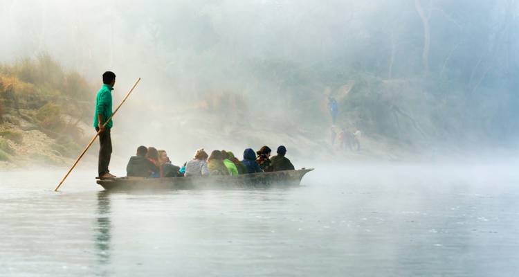 Menschen in einem Kanu auf einem nebligen Fluss.
