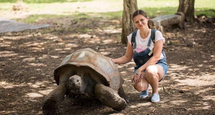 Person posiert mit einer Riesenschildkröte.