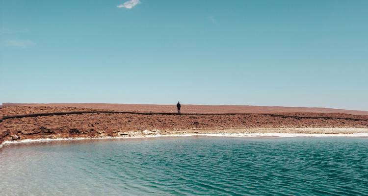 Personne debout près d'un lac sous un ciel dégagé.