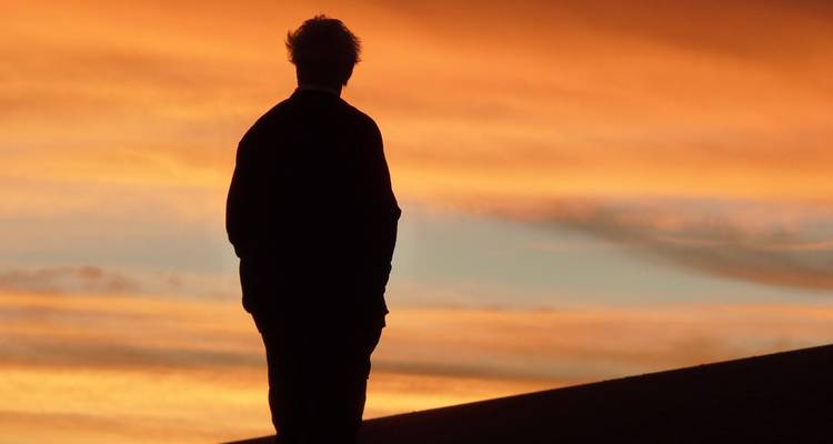 Silhouette d'une personne contre un coucher de soleil éclatant.