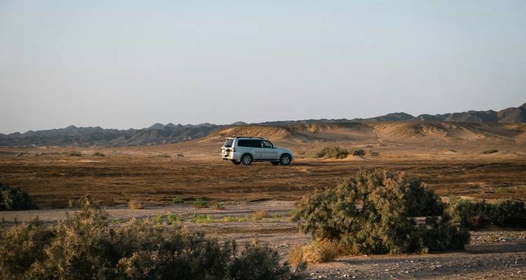 Un véhicule roulant à travers un paysage désertique.