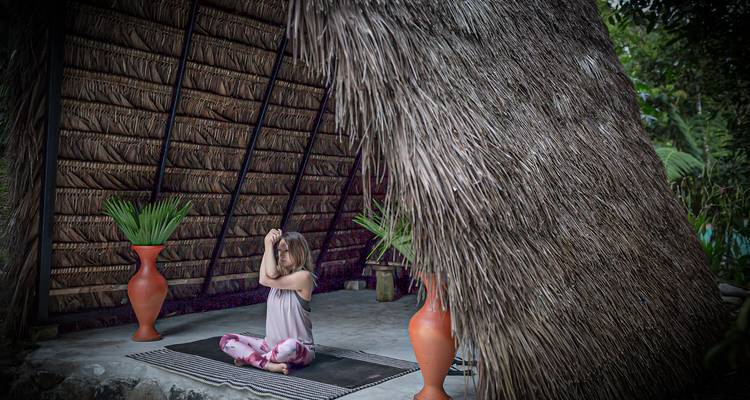 Personne méditant dans une cabane rustique avec des plantes.