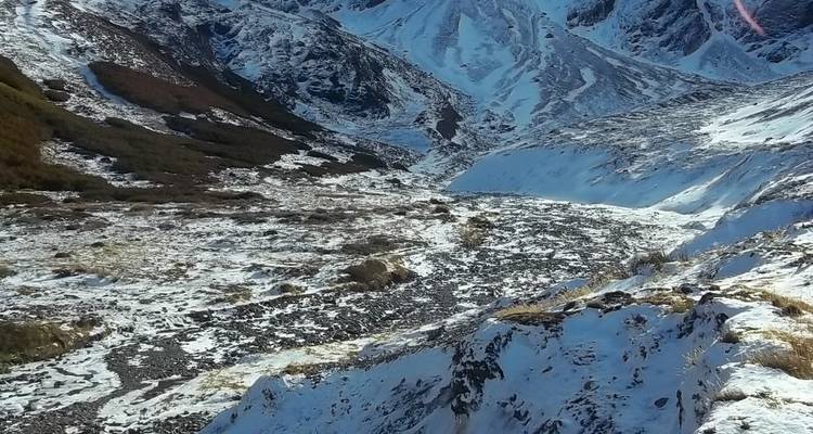 Vallée alpine enneigée avec terrain accidenté et crêtes lointaines sous une lumière douce