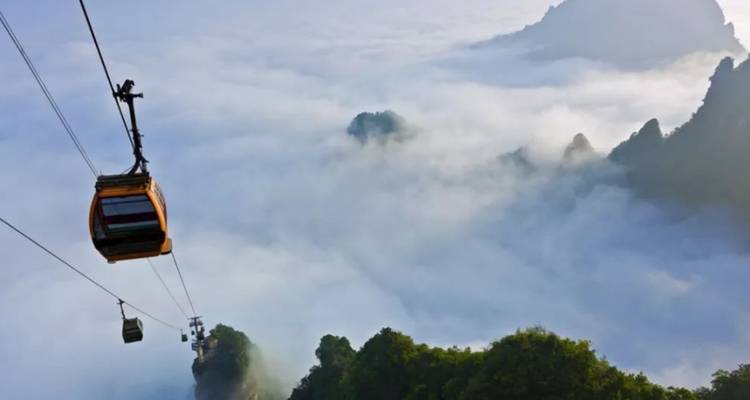 Téléphériques se déplaçant à travers une chaîne de montagnes brumeuse.