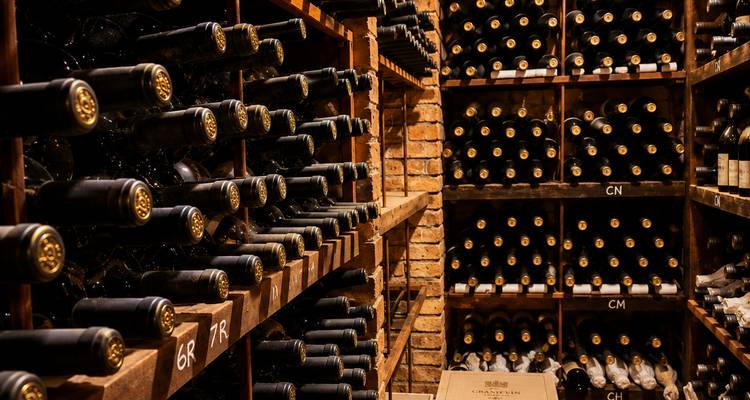 Bodega de vinos con poca luz apilada de piso a techo con botellas envejecidas en Mendoza.