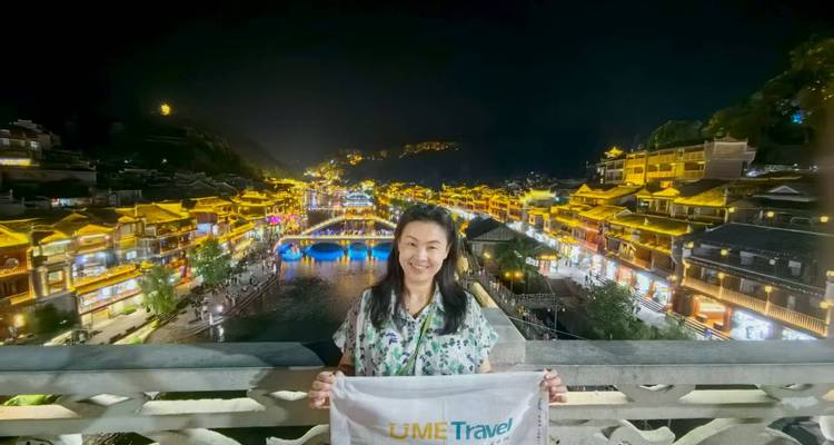 Une femme tenant une banderole devant un décor d'immeubles illuminés la nuit.