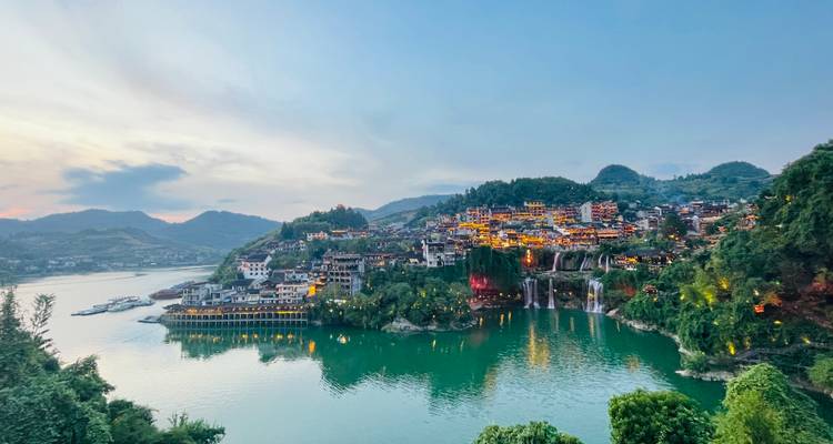 Vue panoramique d'une ville et d'une rivière entourées de collines vertes.