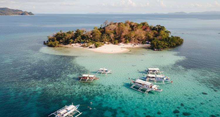 Vue aérienne d'une petite île avec des bateaux dans des eaux turquoise claires.
