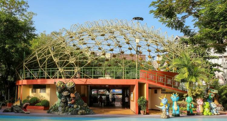 Entrée d'un parc avec une structure de dôme géodésique et des statues colorées.