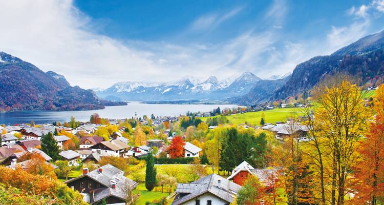 Charmant village autrichien au bord du lac entouré d'arbres d'automne et de montagnes enneigées.